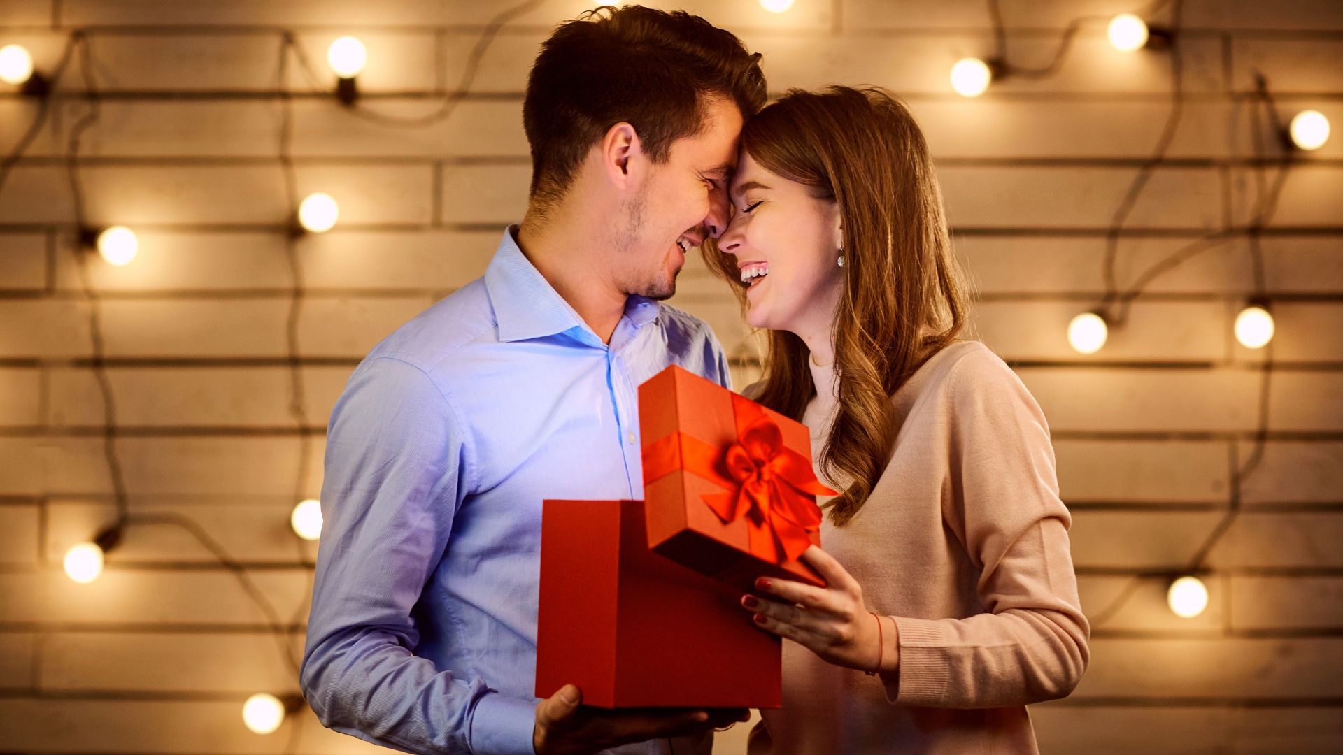 parjea sosteniendo regalo sonrientes y con las caras juntas