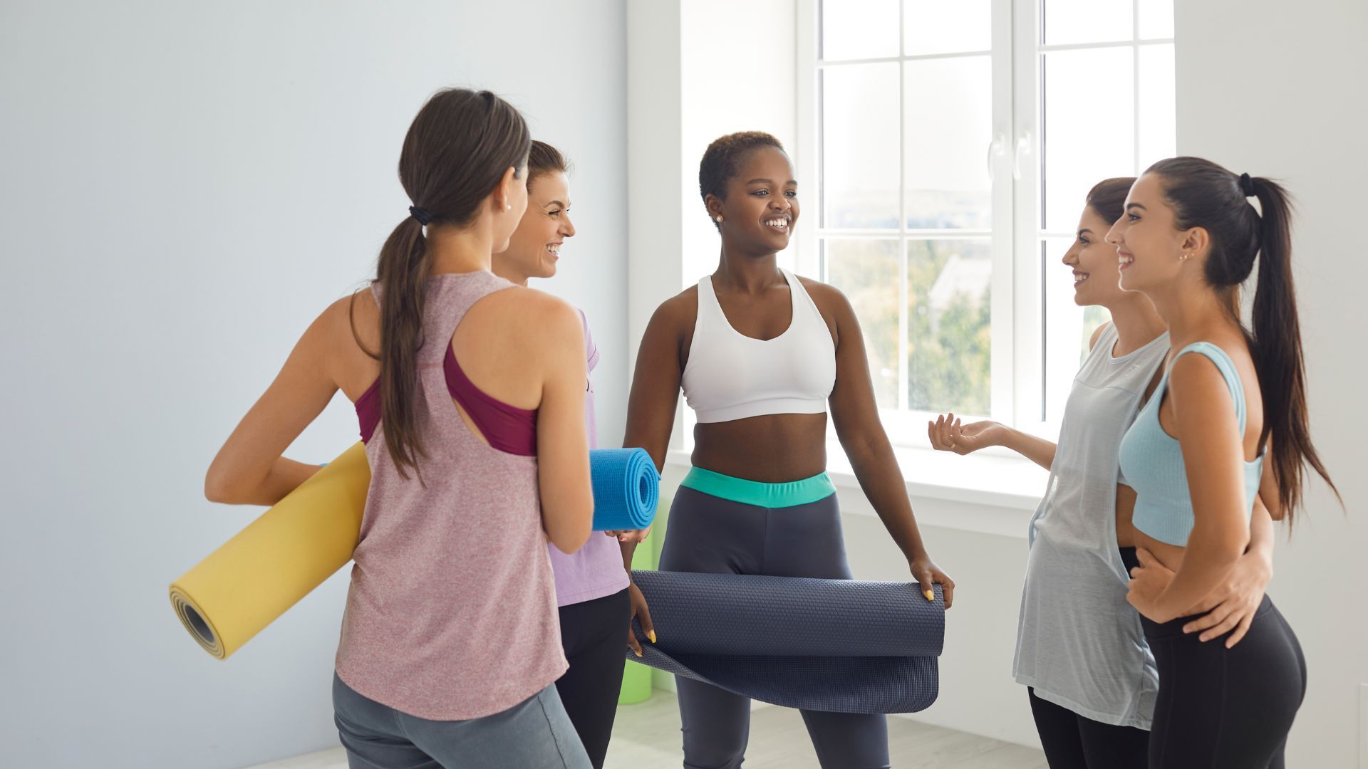 Grupo de mujeres de pie en círculo hablando alegremente después de una clase deportiva