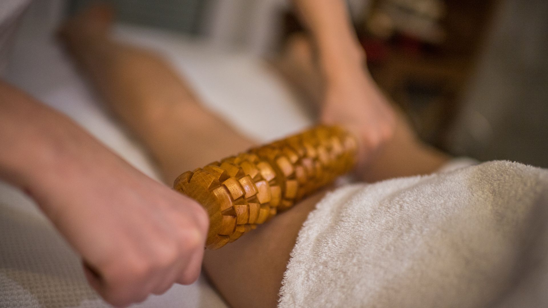 5 beneficicios de la maderoterapia. terapeuta pasando el rodillo por la pierna de una paciente.