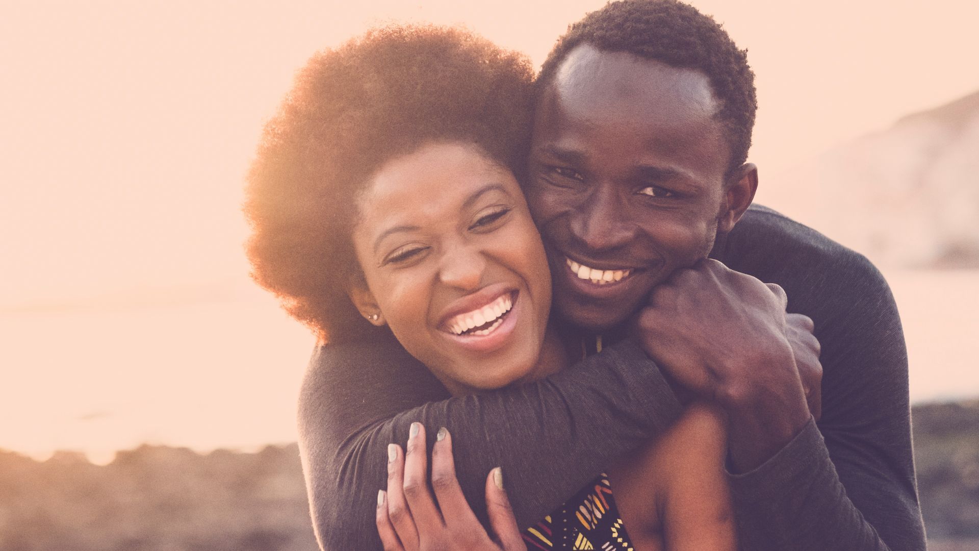 Pareja sonriente y abrazada mirándo a cámara felizmente