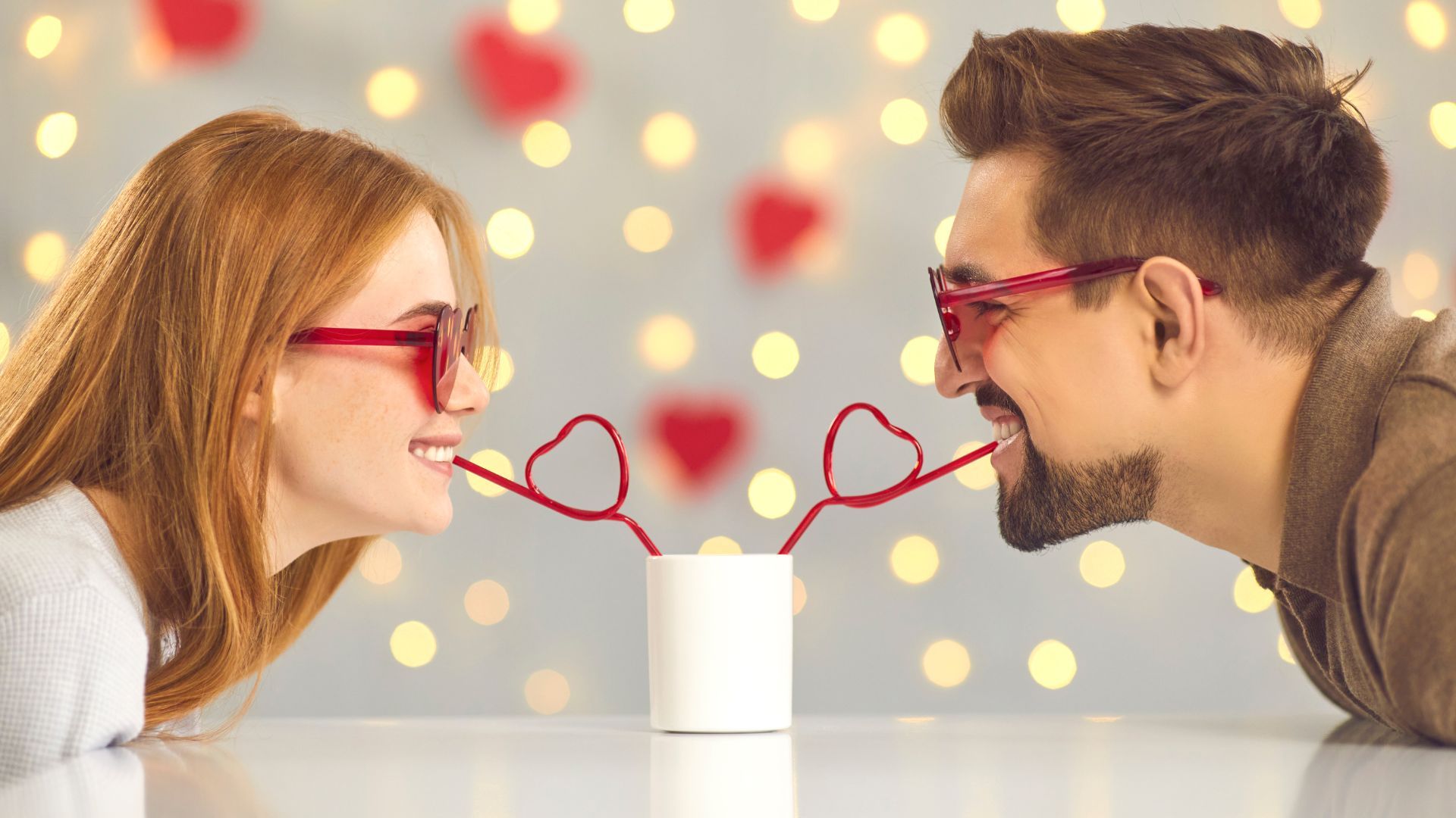 San Valentín día de los enamorados. pareja sonriente mientras sorben de una misma taza con pajitas en forma de corazón